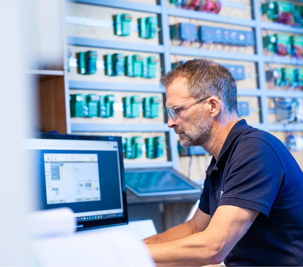 Employee sitting in control room by screens and technical instruments