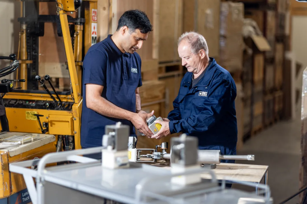 Two employees next to each other looking at an industrial product